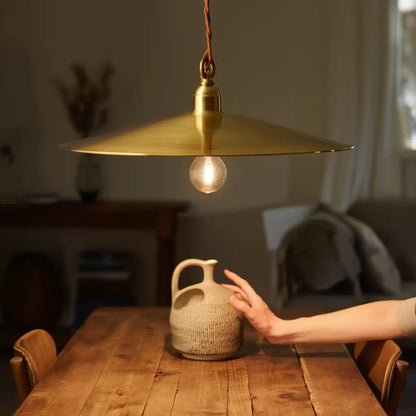 Suspension CANTINA en métal bronze au-dessus d’une table en bois, ampoule lumineuse basse