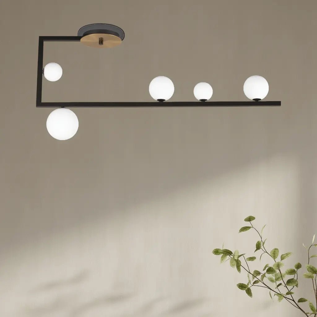 Plafonnier noir moderne avec une barre suspendue et cinq globes en verre soufflé, éclairage élégant.