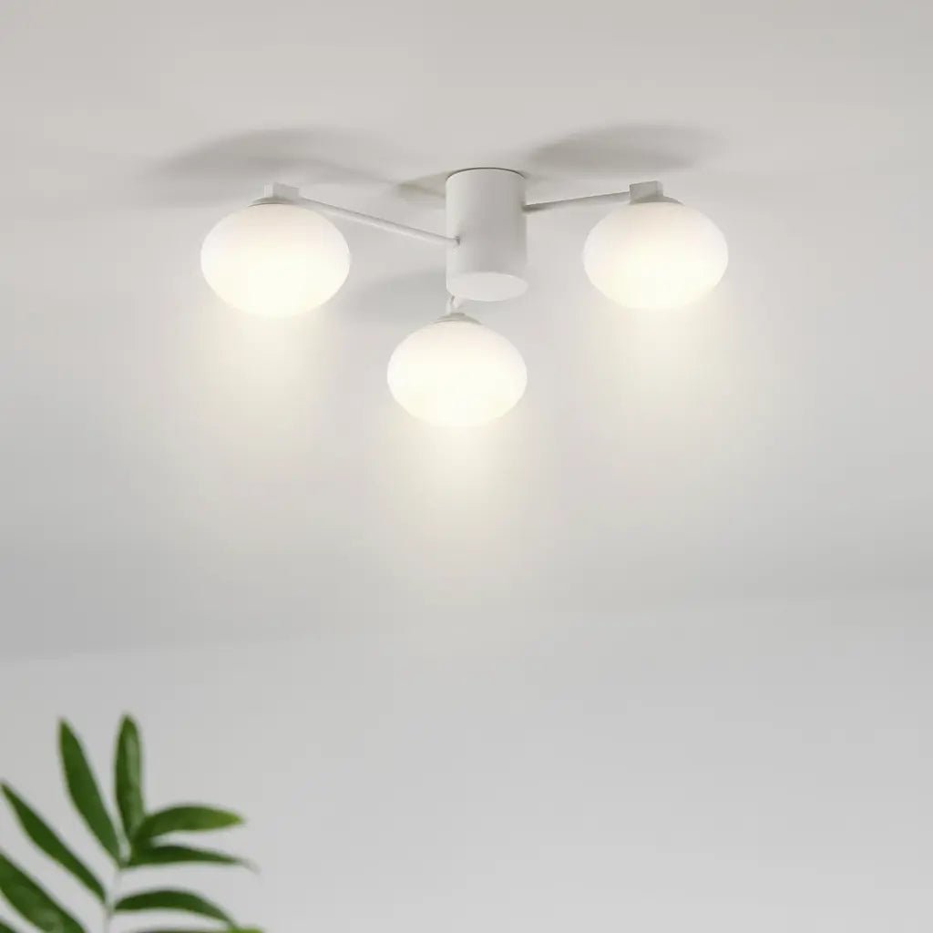 Plafonnier moderne Hermes à 3 globes blancs, fixé au plafond avec bras fins, éclairage lumineux dans une pièce blanche.