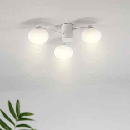 Plafonnier moderne Hermes à 3 globes blancs, fixé au plafond avec bras fins, éclairage lumineux dans une pièce blanche.