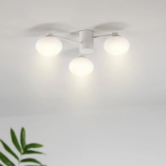 Plafonnier moderne Hermes à 3 globes blancs, fixé au plafond avec bras fins, éclairage lumineux dans une pièce blanche.