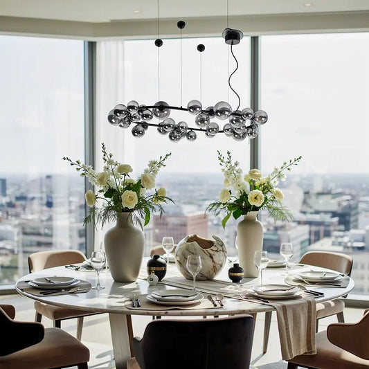 Suspension ovale en verre fumé avec perles sphériques noir mat, au-dessus d’une table ronde