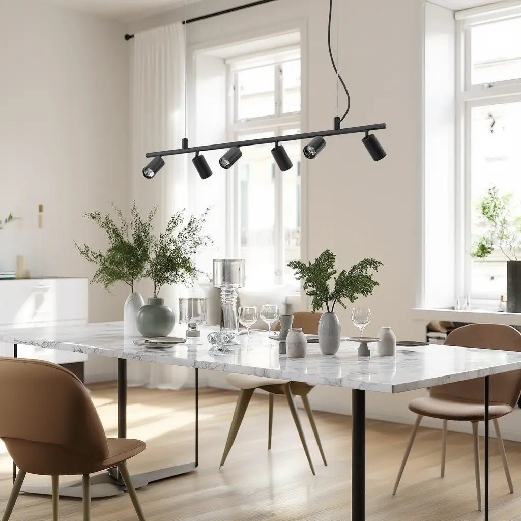 Suspension DYNAMITE SP6 noire au-dessus d’une table de dining moderne en marbre blanc, avec plantes et vaisselle élégante.