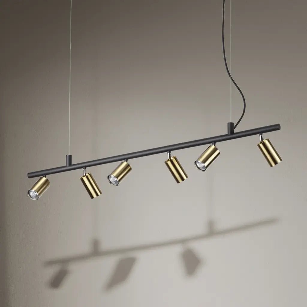 Suspension/DYNAMITE SP6 noire et laiton: rail horizontal noir avec six spots dorés, câbles suspendus au plafond, éclairage directionnel.
