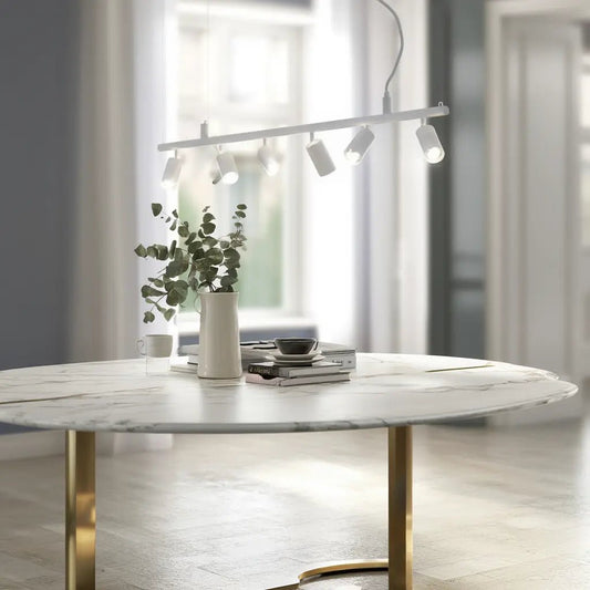 Suspension DYNAMITE SP6 blanche au-dessus d’une table ronde en marbre avec vase, plantes et livres.