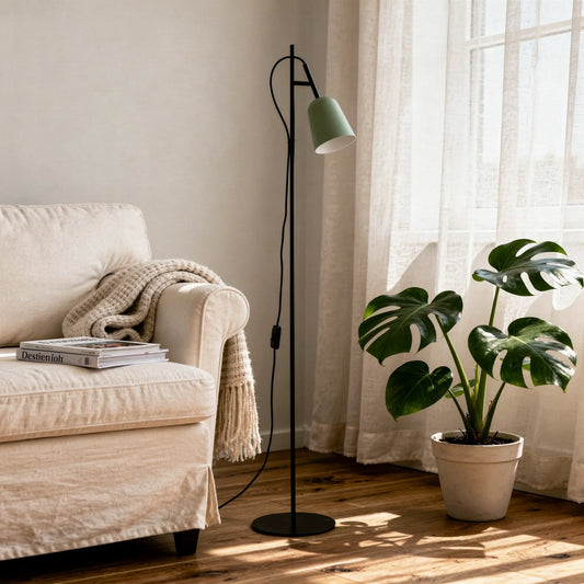 Lampadaire noir à laurel avec abat-jour vert, près d’un canapé beige et d’une plante Monstera dans un intérieur lumineux.