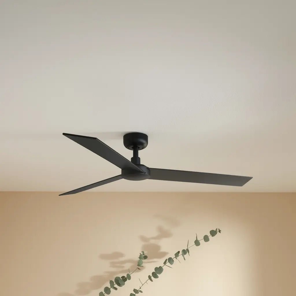 Ventilateur de plafond RUDDER L noir à trois pales installé au plafond dans une pièce, avec plante décorative en bas.