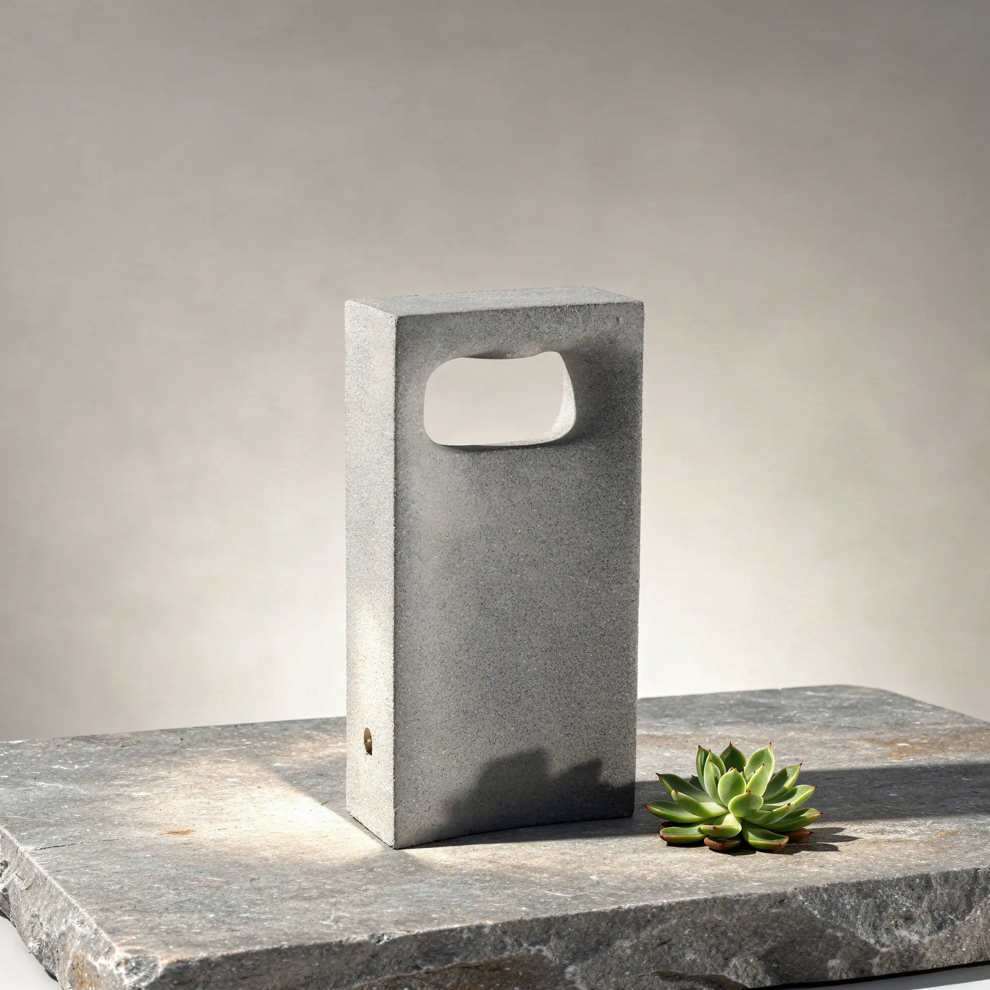 Borne lumineuse LED en béton GLINT-400 8 W pour jardins en situation sur un dallage en pierre