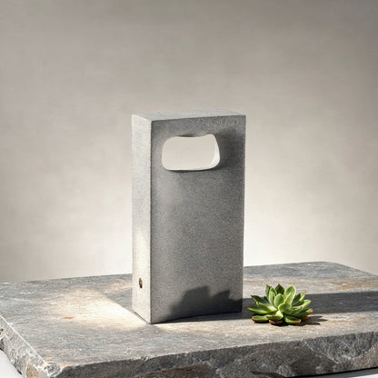 Borne lumineuse LED en béton GLINT-400 8 W pour jardins en situation sur un dallage en pierre